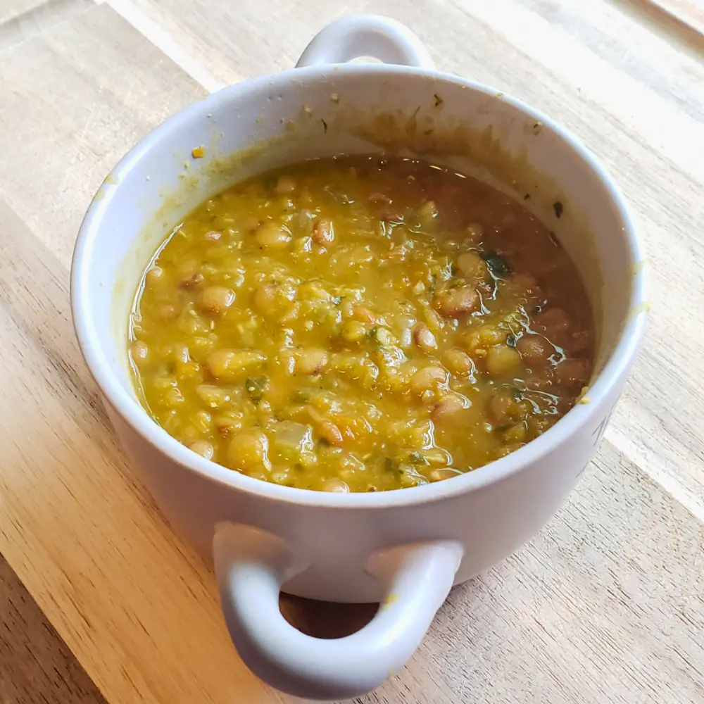 A bowl of hearty vegan lentil soup with carrots, celery, and fresh herbs – a healthy recipe by The Promised Cook.
