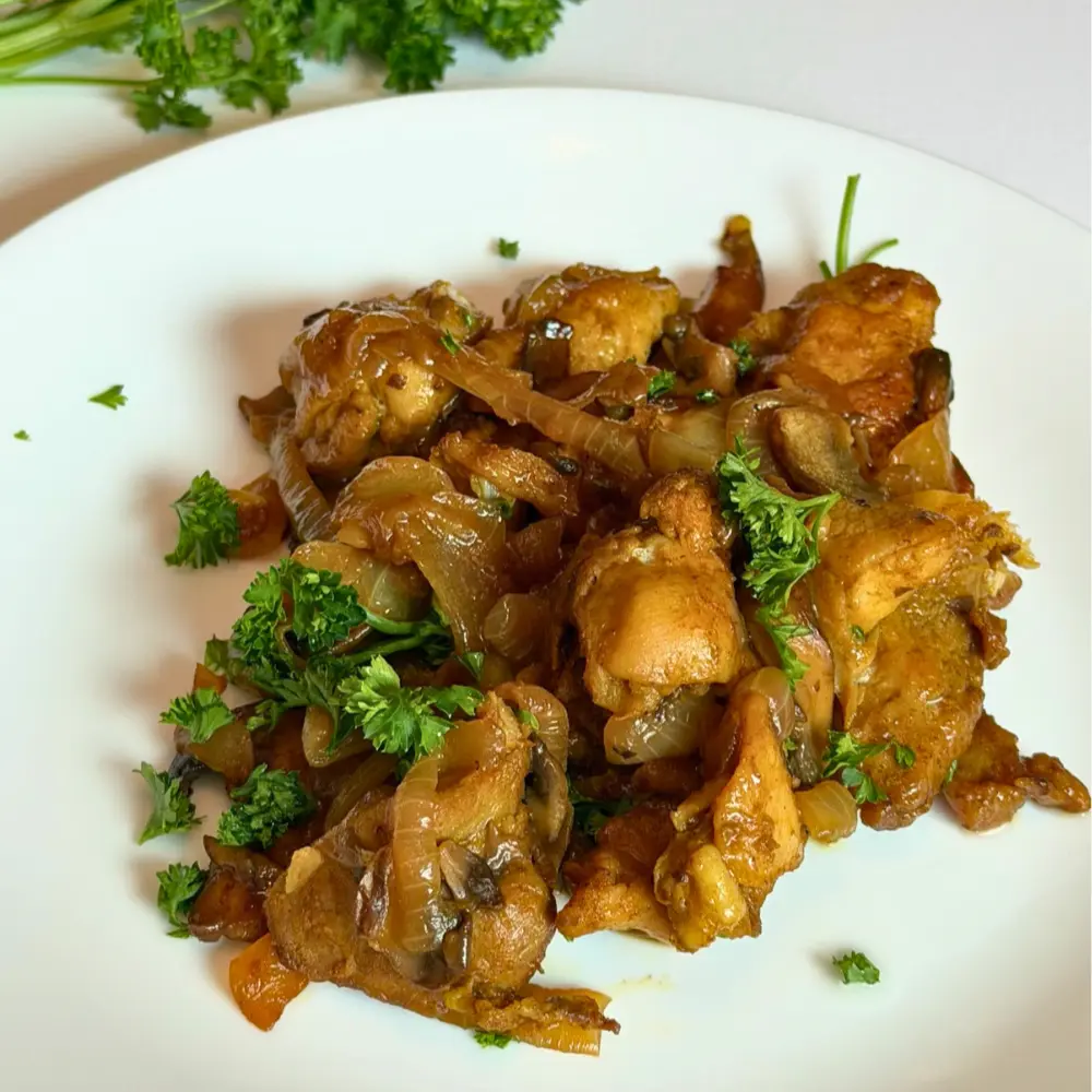 mediterranean-chicken-thighs Juicy Mediterranean chicken thighs with caramelized onions and mushrooms served on a clean white plate.